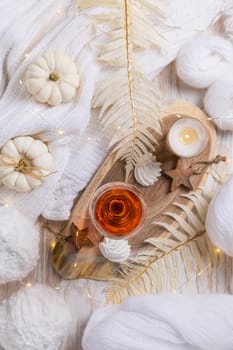 Cosy still life for winter and autumn with glass of pink wine, pumpkin cookie, wool and warm sweater