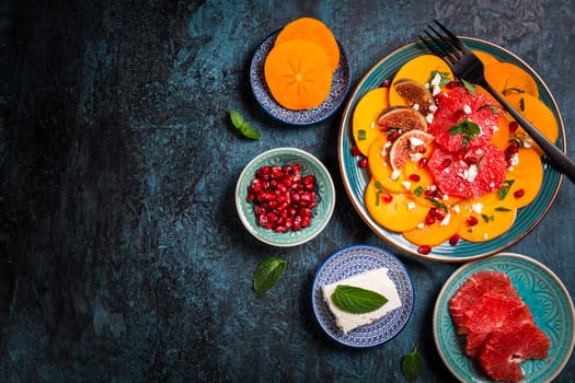 Healthy winter salad - Persimmon carpaccio salad with pomegranate, feta cheese, pink grapefruit and figs