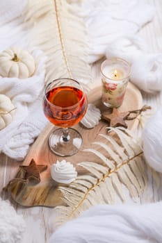 Cosy still life for winter and autumn with glass of pink wine, pumpkin cookie, wool and warm sweater