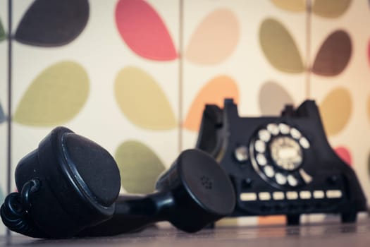 Old retro and vintage rotary phone off the hook, colorful wallpaper, selective focus and copy space.