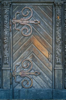 Vintage, old wooden door in baroque style with iron hinges and frame ornaments. Cathedral in Szczecin, Poland