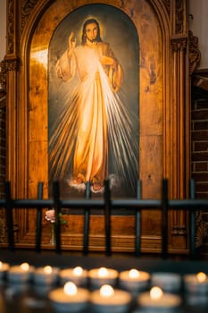 Szczecin, Poland, June 2019 Painting of Yeezus Christ with lit candles in The Cathedral Basilica of St James the Apostle