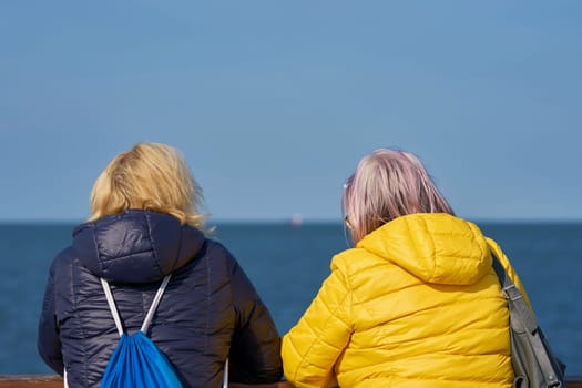 two women during a conversation at a bridge railing on the beach of the Polish Baltic Sea coast near Swinoujscie