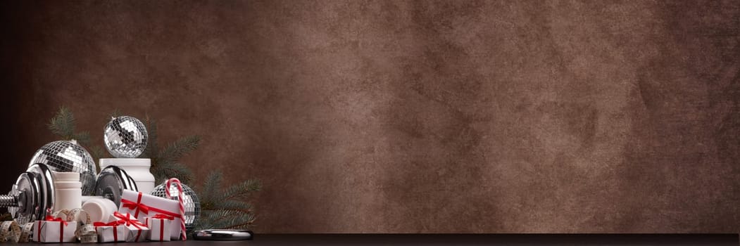 Sports nutrition (supplements), sports equipment, fir branch,  gift boxes, Christmas ornaments on dark brown background with copy space. Fitness, sport, healthy lifestyle concept. New Year. Christmas.