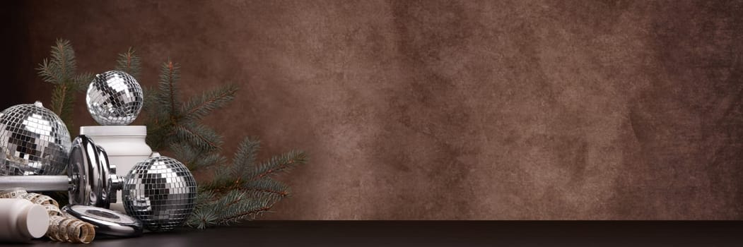Sports nutrition (supplements), sports equipment, branch of fir,  Christmas ornaments on dark brown background with copy space. Fitness, sport or healthy lifestyle concept. New Year and Christmas.