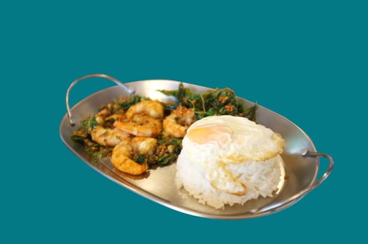 Stirred-fry shrimps or prawns with basil leaves, fried egg over rice on blue background . Thai food