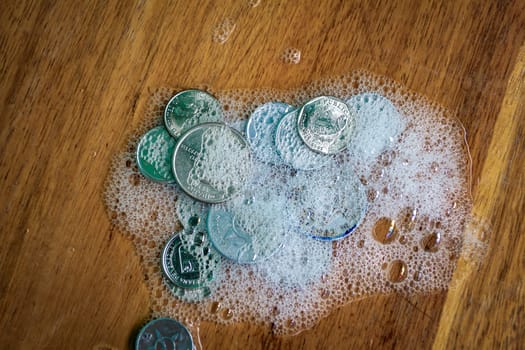 Group of coins covered in foam on a wooden surface