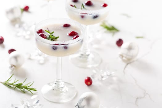 White Christmas margarita punch with cranberries and rosemary on marble background