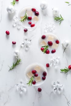 White Christmas margarita punch with cranberries and rosemary on marble background