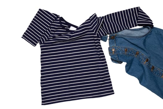 Closeup of folded cute sleeveless blue denim overall dress and striped t-shirt for little child girl isolated on a white background. Jeans fashion for kids.