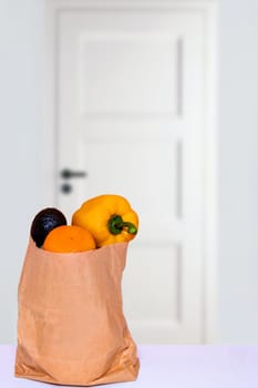 Coronavirus quarantine concept. Contactless delivery service of a bag with vegetables placed at the door of house during pandemic. Stay at home and avoiding social contact and distance.