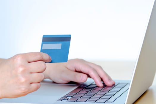 A Person online shopping with a credit card and a laptop.