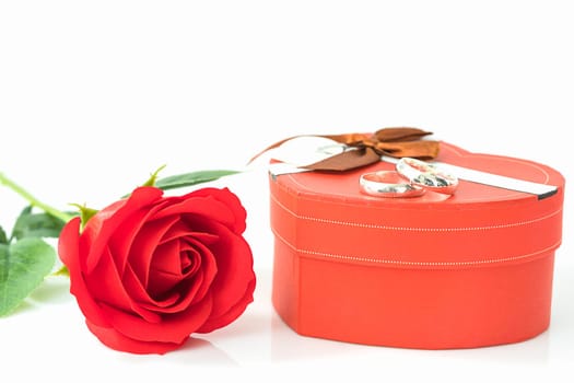 Close up red rose and heart-shaped box with wedding ring on white background, Wedding concept with roses and red heart-shaped box