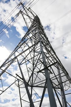 Close up vertical image of the corner of a tall metal electrical transfer tower pylon. Lines of the lattice work converge towards the top. Full frame
