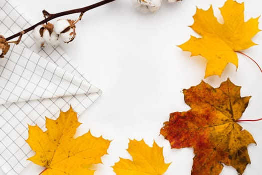 Autumn vibe composition. Blank greeting card mockup. PErfume jar, colorful maple leaves. White table background. Flat lay, top view