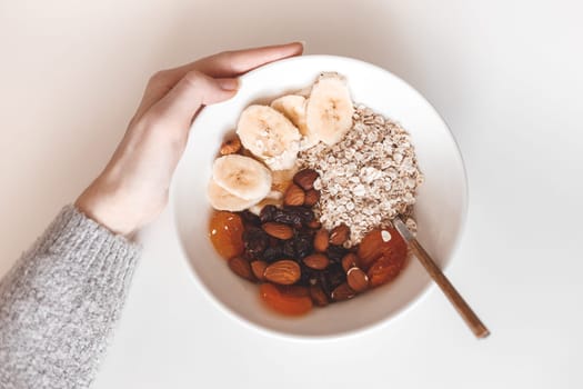 Carbohydrate healthy breakfast. Oatmeal with dried fruits on a white plate. View from above