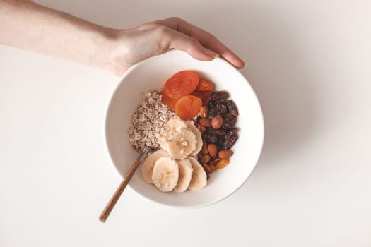 Carbohydrate healthy breakfast. Oatmeal with dried fruits on a white plate. View from above