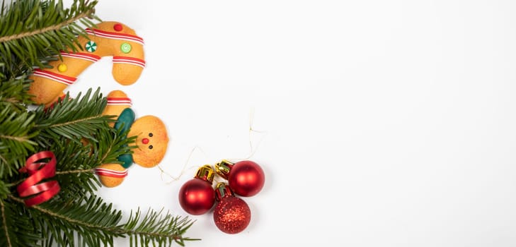 Christmas background with gingerbread cookies and pine tree branch on white.