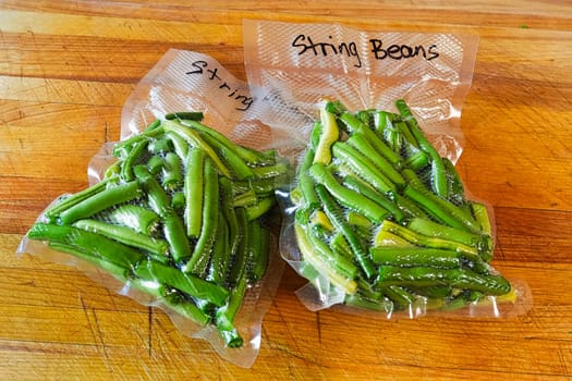 Two packages of fresh green beans vacuum sealed into bags.