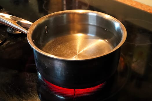 A pot of water simmering on a hot stove element.