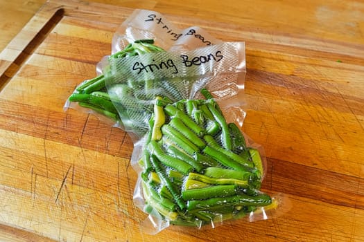 Two packages of fresh green beans vacuum sealed into bags.