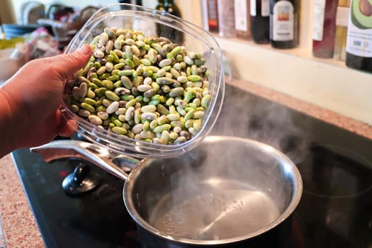 Pouring fresh beans into a simmering pot of water.