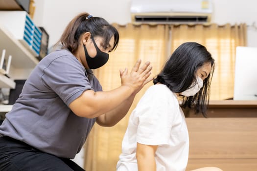 Quarantine asian woman do massage at home with face mask while city lockdown for social distance due to coronavirus pandemic. Massage is one of service business that shutdown while city lockdown.