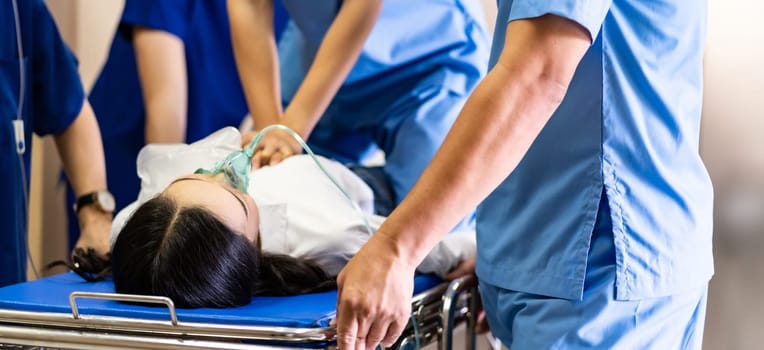Panoramic Close up Medical team do CPR to seriously injured patient with oxygen mask while push gurney stretcher bed to Operating Room. Emergency health care and medical hospital concept.