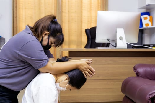 Quarantine asian woman do massage at home with face mask while city lockdown for social distance due to coronavirus pandemic. Massage is one of service business that shutdown while city lockdown.