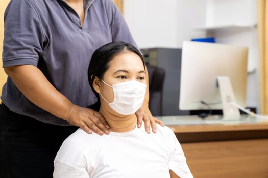 Quarantine asian woman do massage at home with face mask while city lockdown for social distance due to coronavirus pandemic. Massage is one of service business that shutdown while city lockdown.