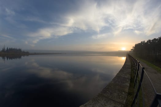 Sunset and clouds reflected in the water of redmires reservoir near sheffield. Level horizon, but fish eye distortion elsewhere. Expansive cloudscape