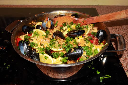 A pan of seafood paella ready to be served on the stove.