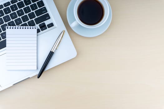 Laptop, notepad, fountain pen and cup of coffee on wooden background. Business and copy space concept..