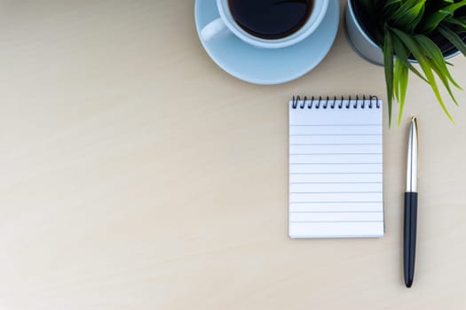 Fountain pen, decorative plant, notepad and cup of coffee on wooden background. Business and copy space concept..