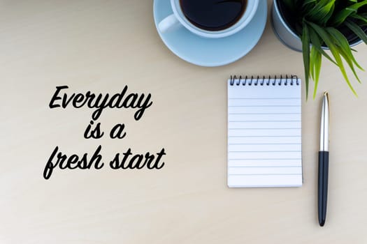 EVERYDAY IS A FRESH START text with fountain pen, notepad, decorative flower and cup of coffee on wooden background. Business and copy space concept..