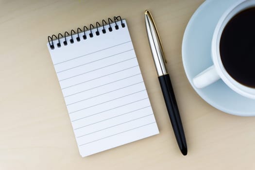 Fountain pen, notepad and cup of coffee on wooden background. Business and copy space concept..