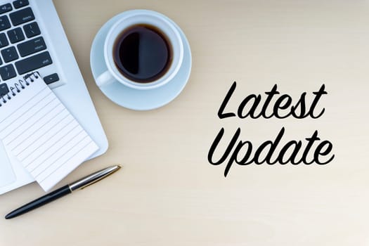 LATEST UPDATE text with fountain pen, notepad, laptop and cup of coffee on wooden background. Business and copy space concept..