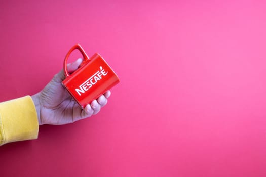 Kuala Lumpur, Malaysia - November 12, 2020 : Hand holding Nescafe Mug on red background
