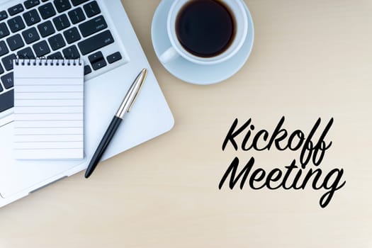 KICKOFF MEETING text with fountain pen, notepad, laptop and cup of coffee on wooden background. Business and copy space concept..