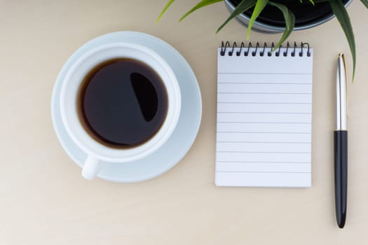 Fountain pen, decorative plant, notepad and cup of coffee on wooden background. Business and copy space concept..