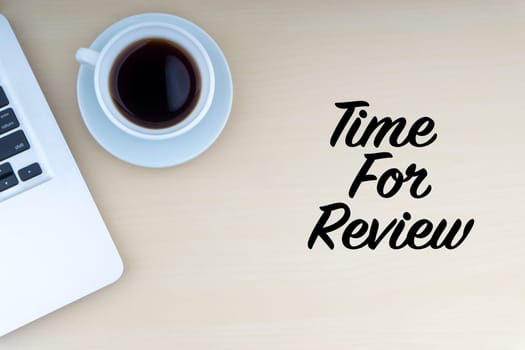 TIME FOR REVIEW text with laptop and cup of coffee on wooden background. Business and copy space concept..