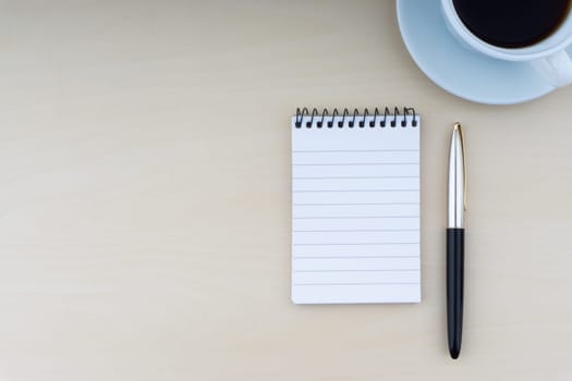 Fountain pen, notepad and cup of coffee on wooden background. Business and copy space concept..