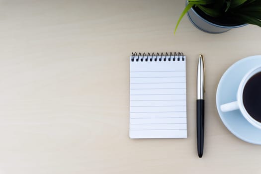 Fountain pen, decorative plant, notepad and cup of coffee on wooden background. Business and copy space concept..