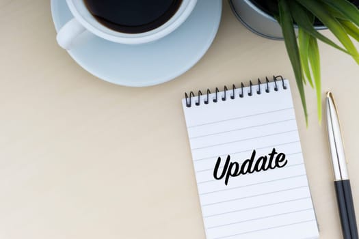 UPDATE text with fountain pen, notepad, decorative flower and cup of coffee on wooden background. Business and copy space concept..