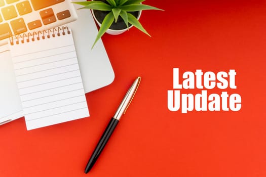 LATEST UPDATE text with notepad, laptop, fountain pen and decorative plant on red background. Business and Copy Space Concept