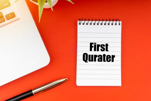 FIRST QUARTER text with notepad, laptop, fountain pen and decorative plant on red background. Business and Copy Space Concept
