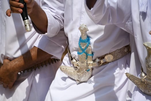 Men in Oman wear a scimitar dagger over the traditional robe of the Dishdasha