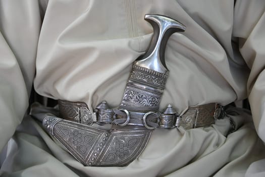 On the traditional festive garment of the Dischdasha,Omani males wear a scimitar dagger as a status symbol