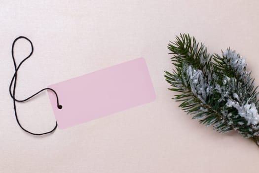Template for christmas sale. A blank paper price tag and a fir branch on a bright glittering background. Concept of winter or Black Friday sale. Empty space for design.