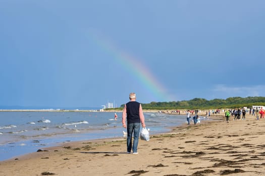 Holidaymakers on the beach of Swinoujscie on the Baltic Sea. In the background a rainbow.